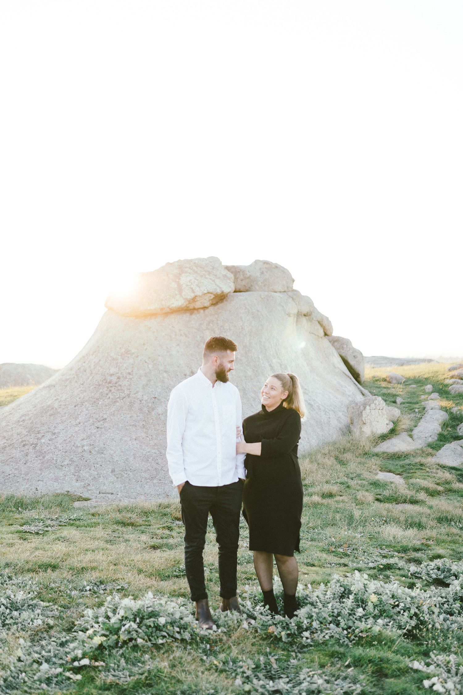 A couple stands together against a backdrop of white limestone rock formations in nature.
