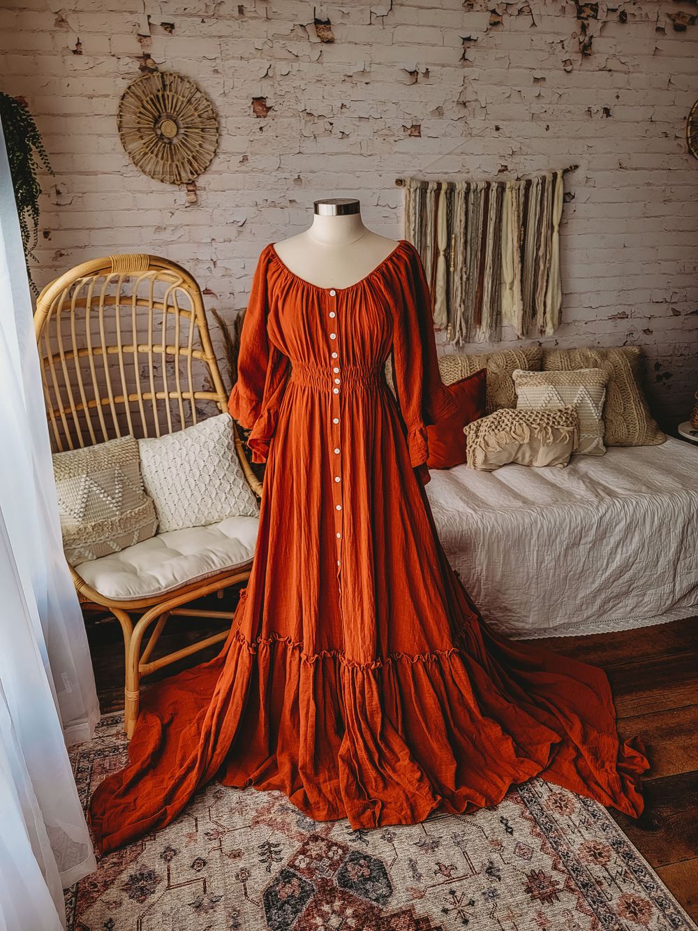 Burnt orange boho button-front maxi dress with ruffle hem and long sleeves on mannequin.