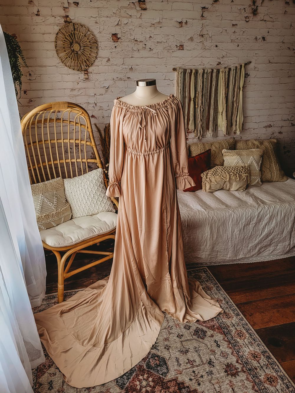 Dusty rose tan off-shoulder gathered maxi dress with long sleeves and train on mannequin.