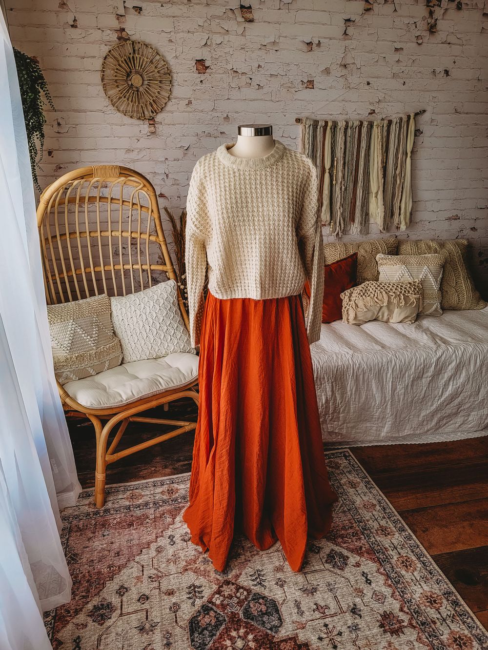 Cream chunky knit sweater paired with rust orange maxi skirt on mannequin in boho studio.