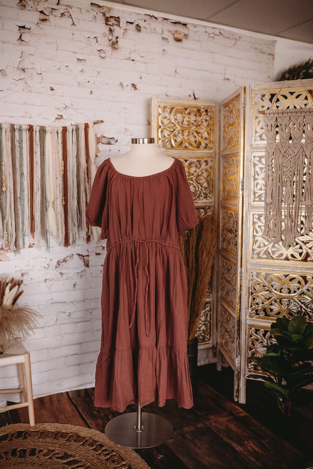 Rust brown off-shoulder flutter sleeve tiered midi dress on mannequin in boho studio setting.