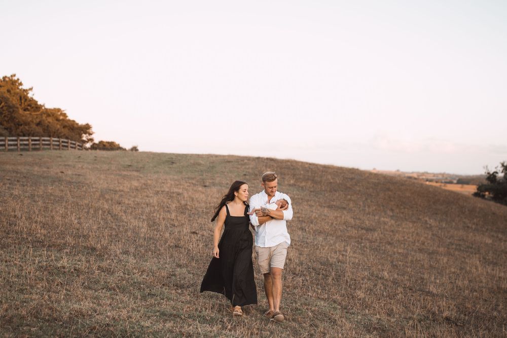 Couple walking together across a scenic hillside during golden hour.