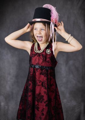 Playful sequence showing someone posing with a pink feathered hat and burgundy dress.