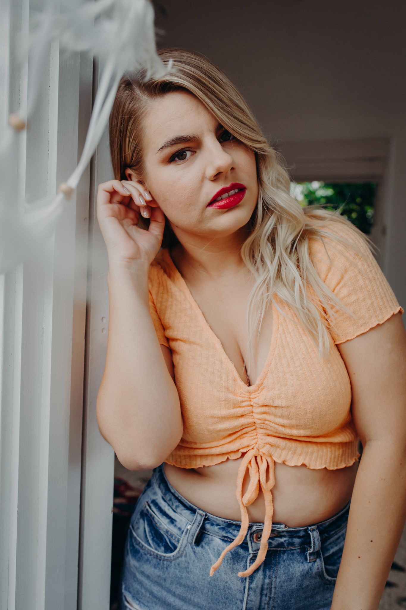 Casual summer portrait in peach crop top and denim.