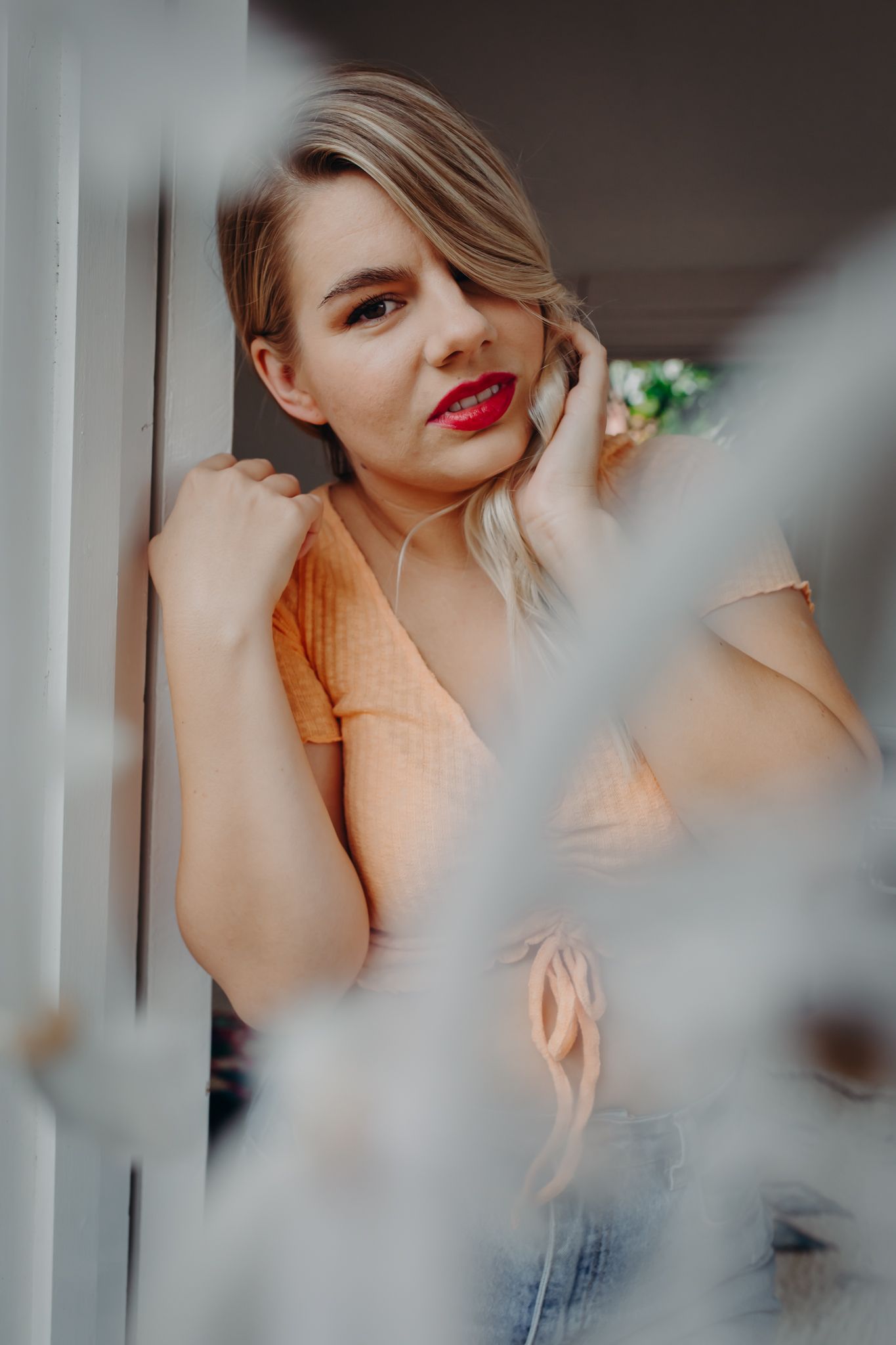 Portrait with soft lighting wearing peach top and bold red lipstick.