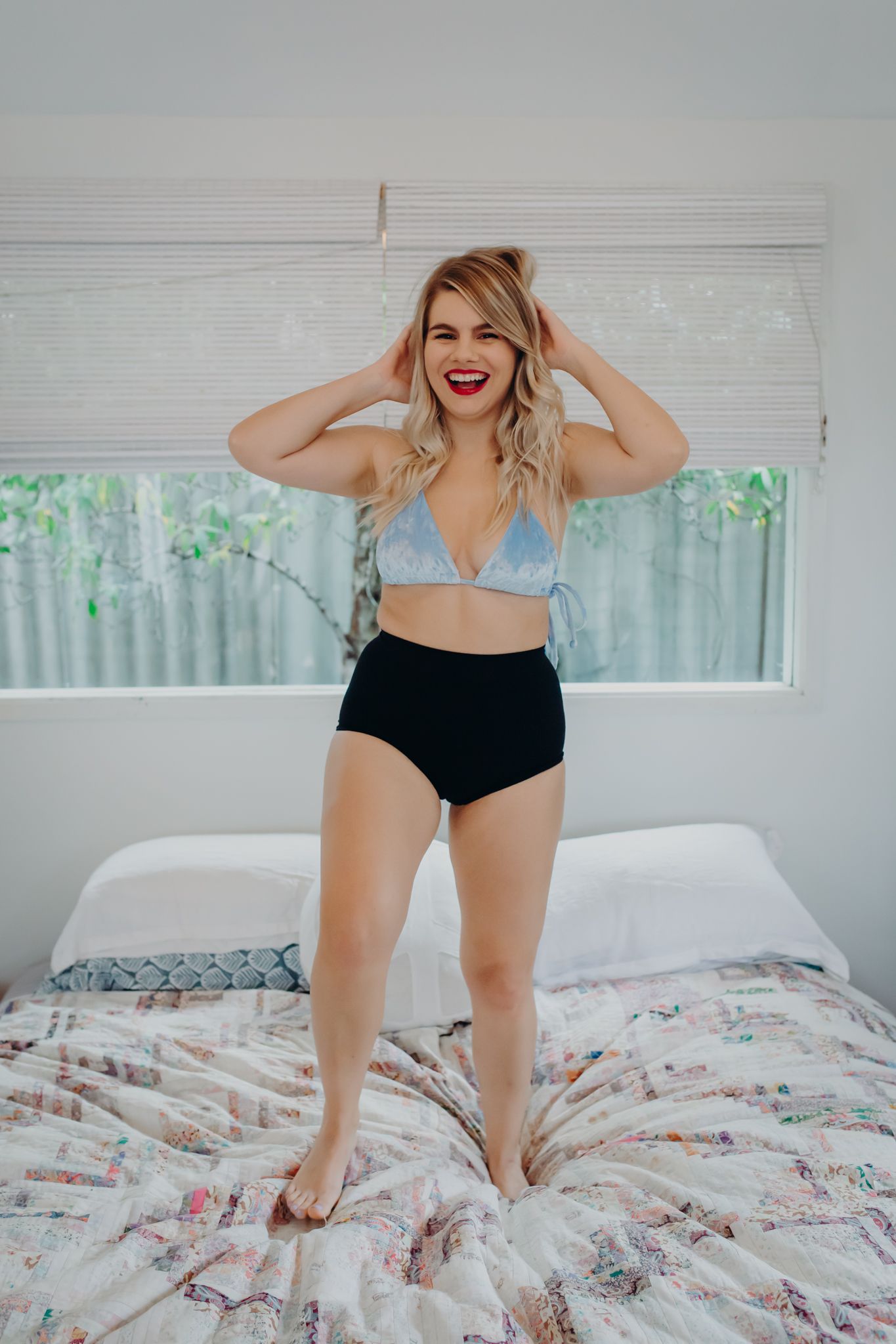 Energetic portrait jumping on bed in retro-style swimwear.