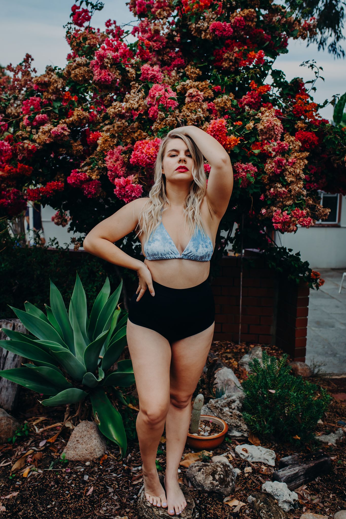 Outdoor fashion portrait against pink flowering bush and agave plants.