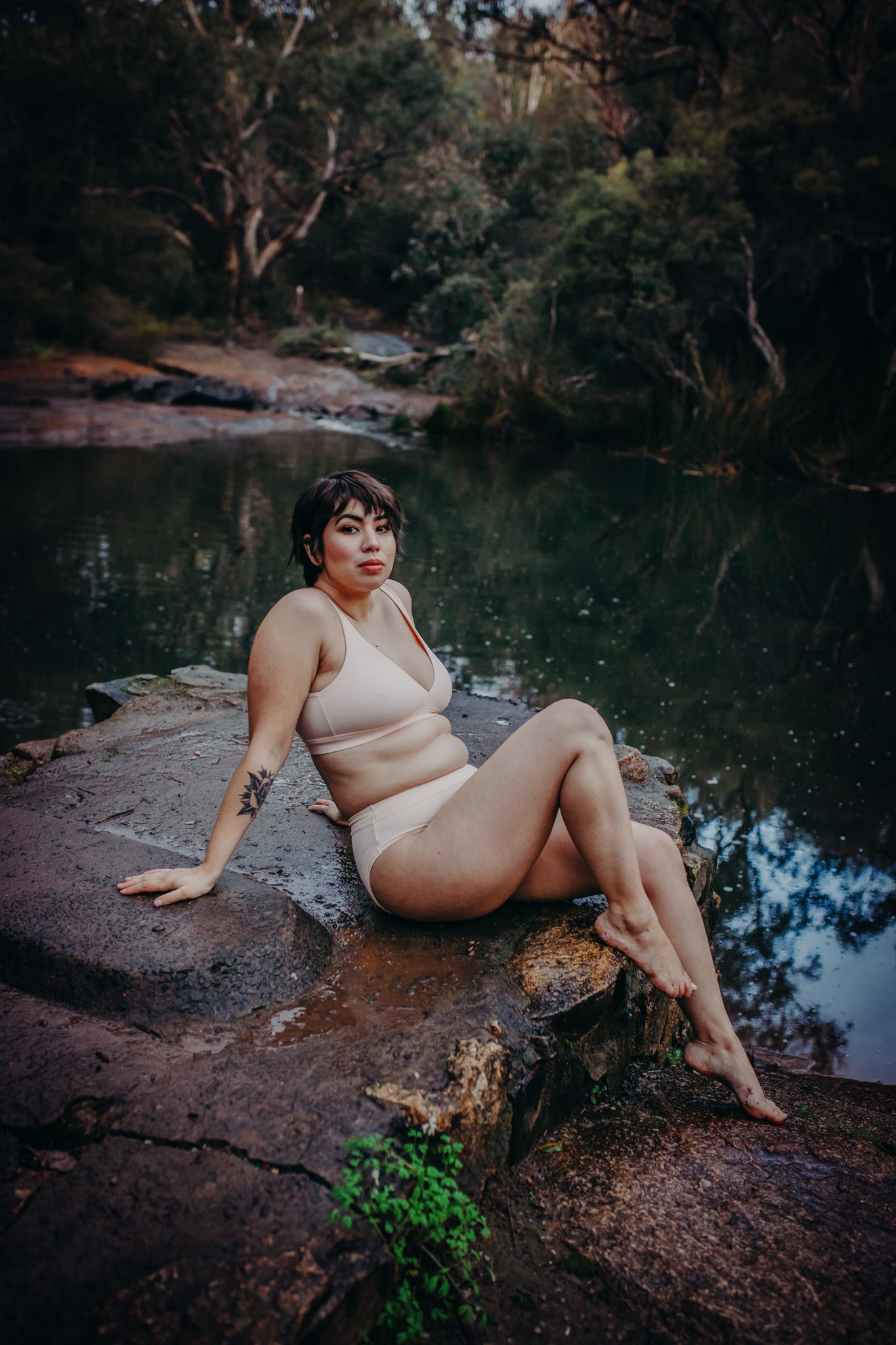 Artistic boudoir photography at a secluded pond featuring moody natural lighting and reflective water.