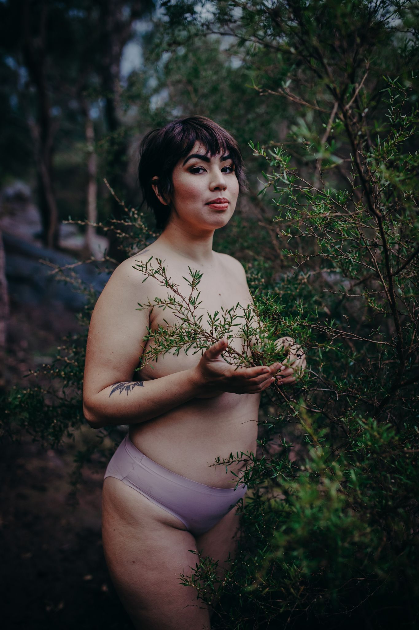 Body positive portrait incorporating natural elements and soft lighting by a forest pond.