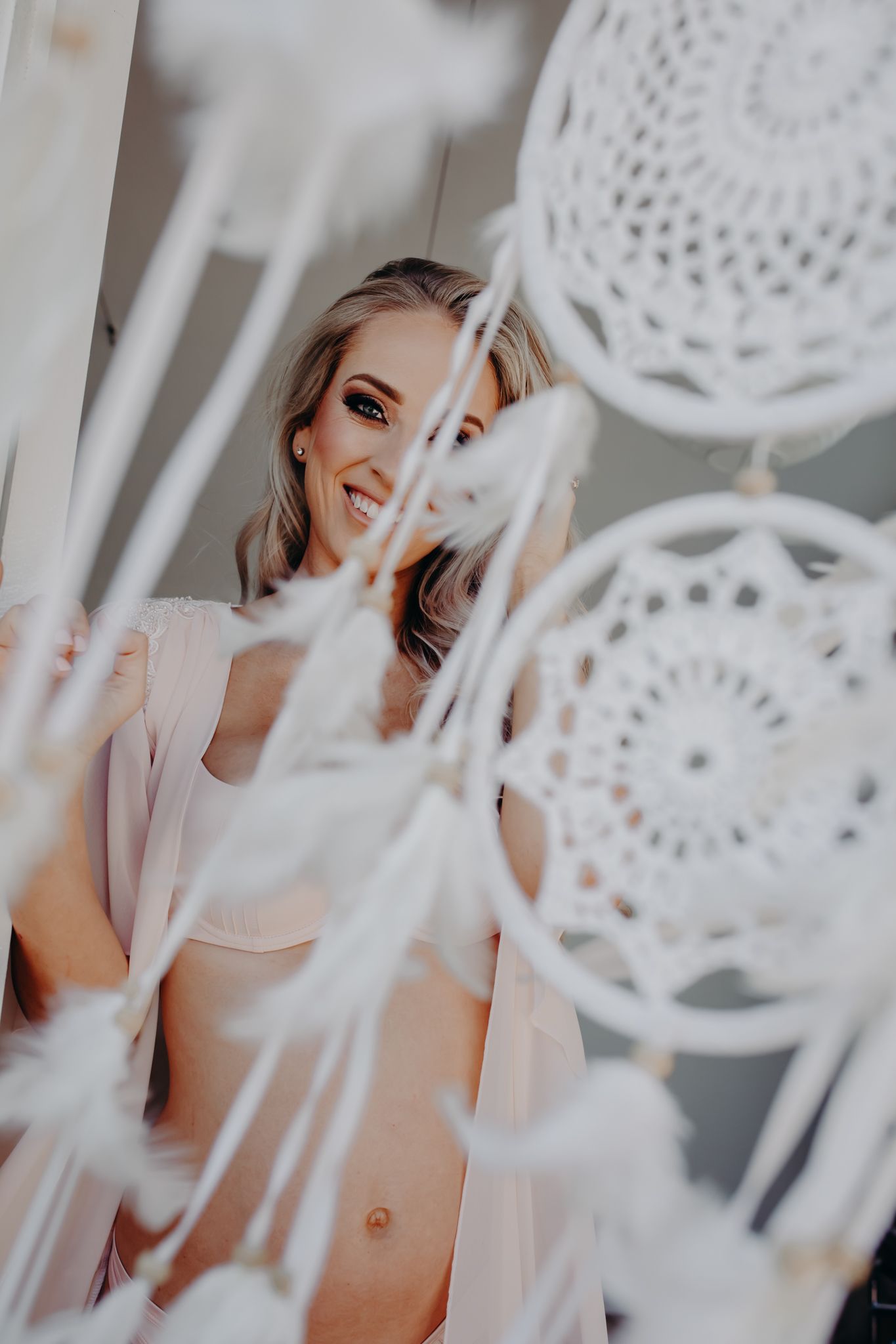 Dreamy bridal portrait through white lace dreamcatchers with soft natural lighting.