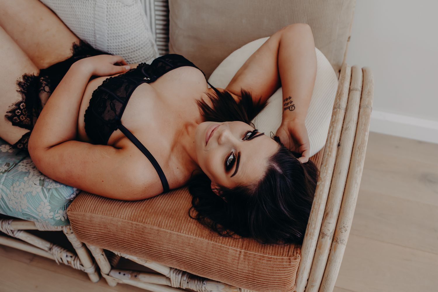Intimate portrait in black lingerie on a couch with natural window lighting.