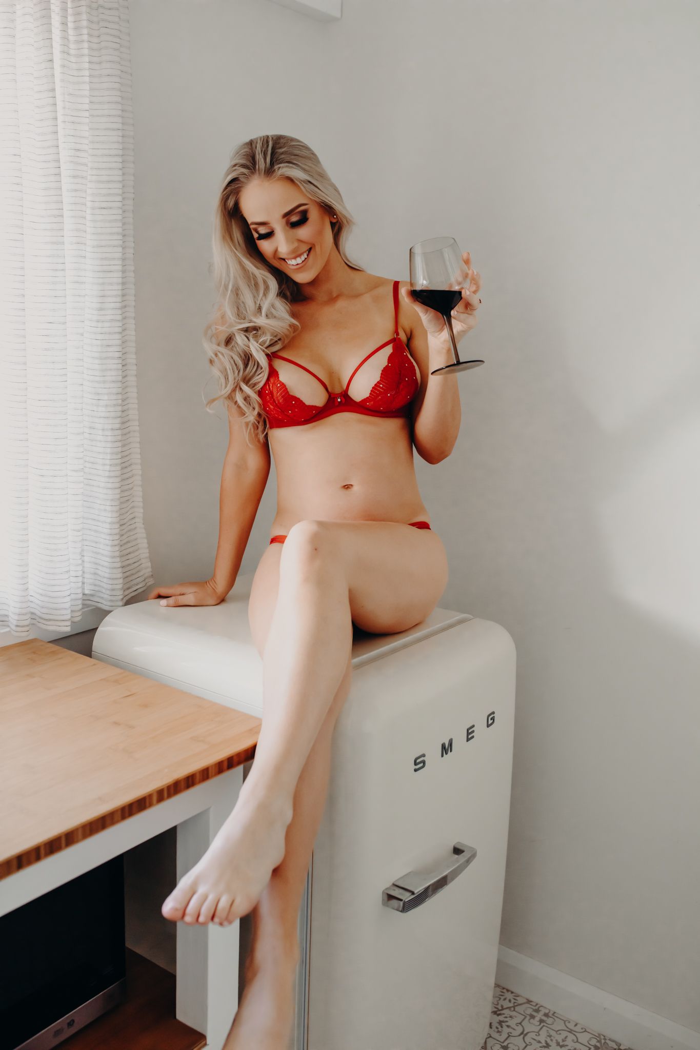 Elegant boudoir photo on vintage SMEG fridge in red lingerie.