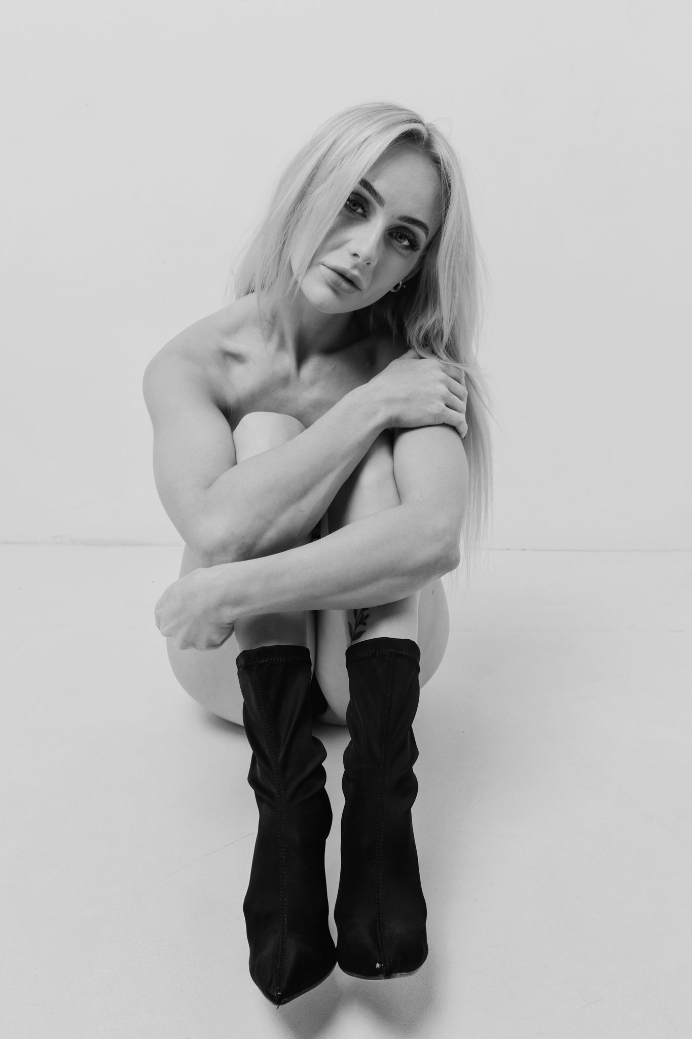 Minimalist black and white portrait showcasing natural form and dark footwear.