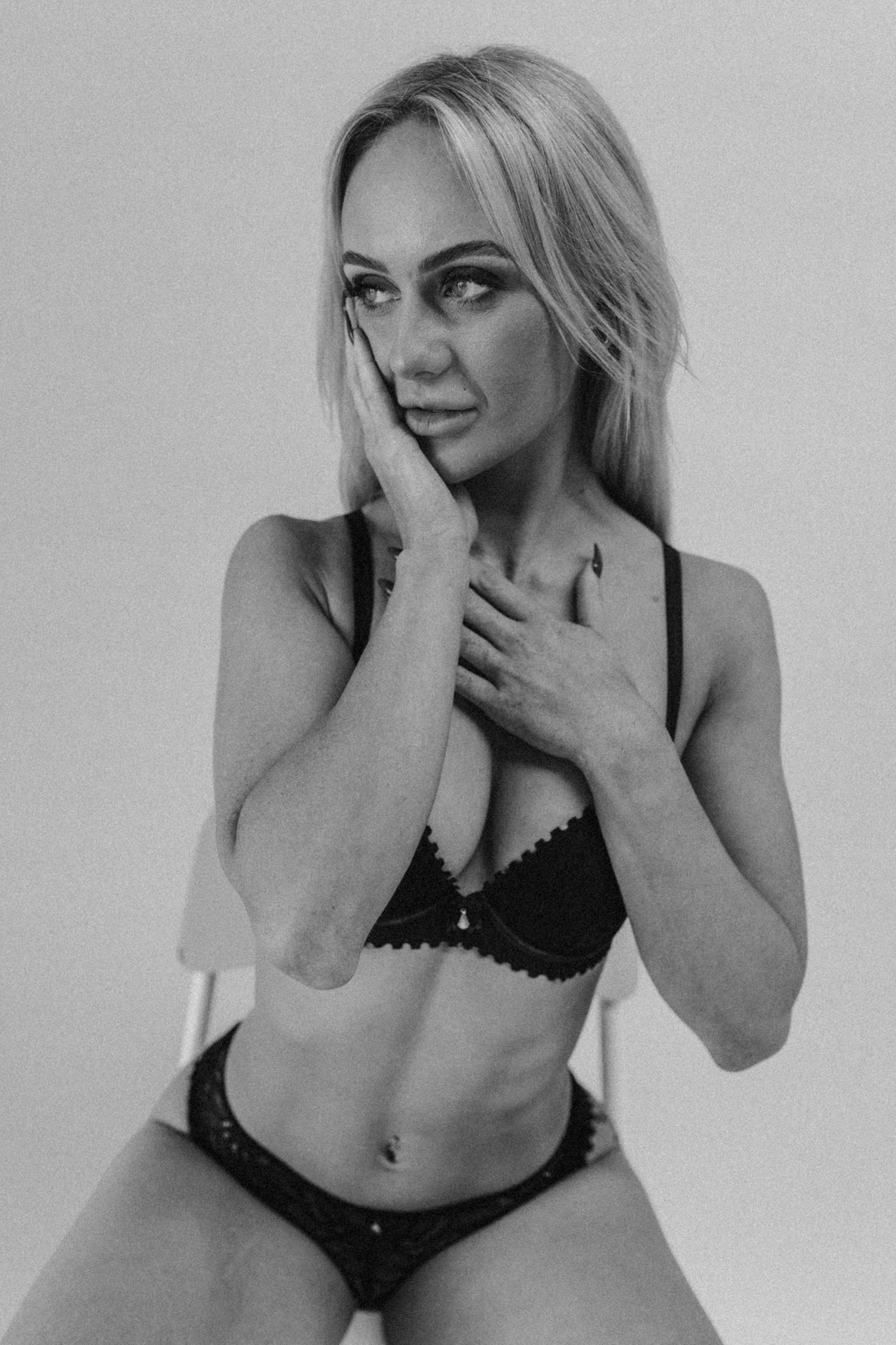 Dramatic black and white boudoir portrait showing intimate pose in black lingerie.