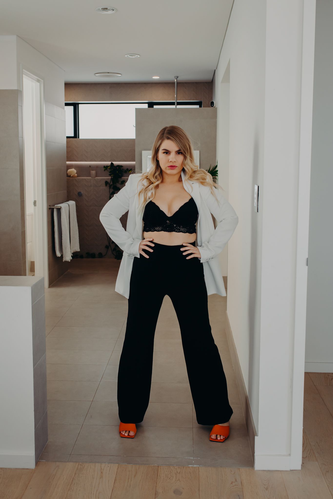 Fashion portrait in modern interior wearing black pants and white cardigan.