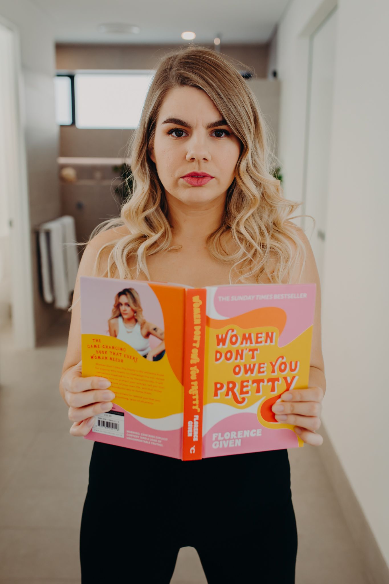 Person holding book titled 'Women Don't Owe You Pretty' in indoor setting.