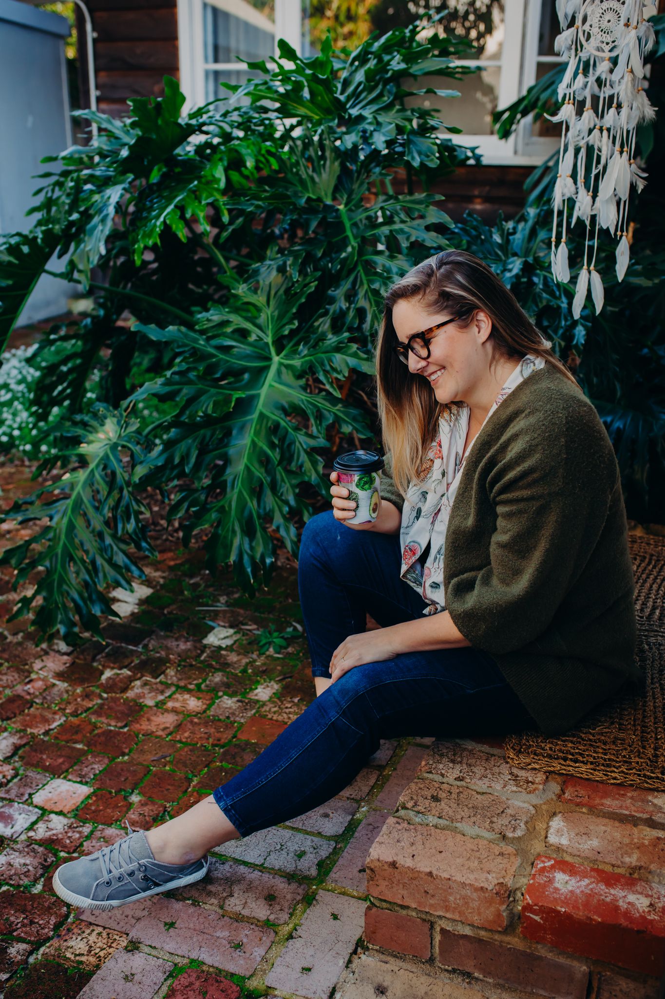Candid shot of someone relaxing on brick steps surrounded by tropical plants.