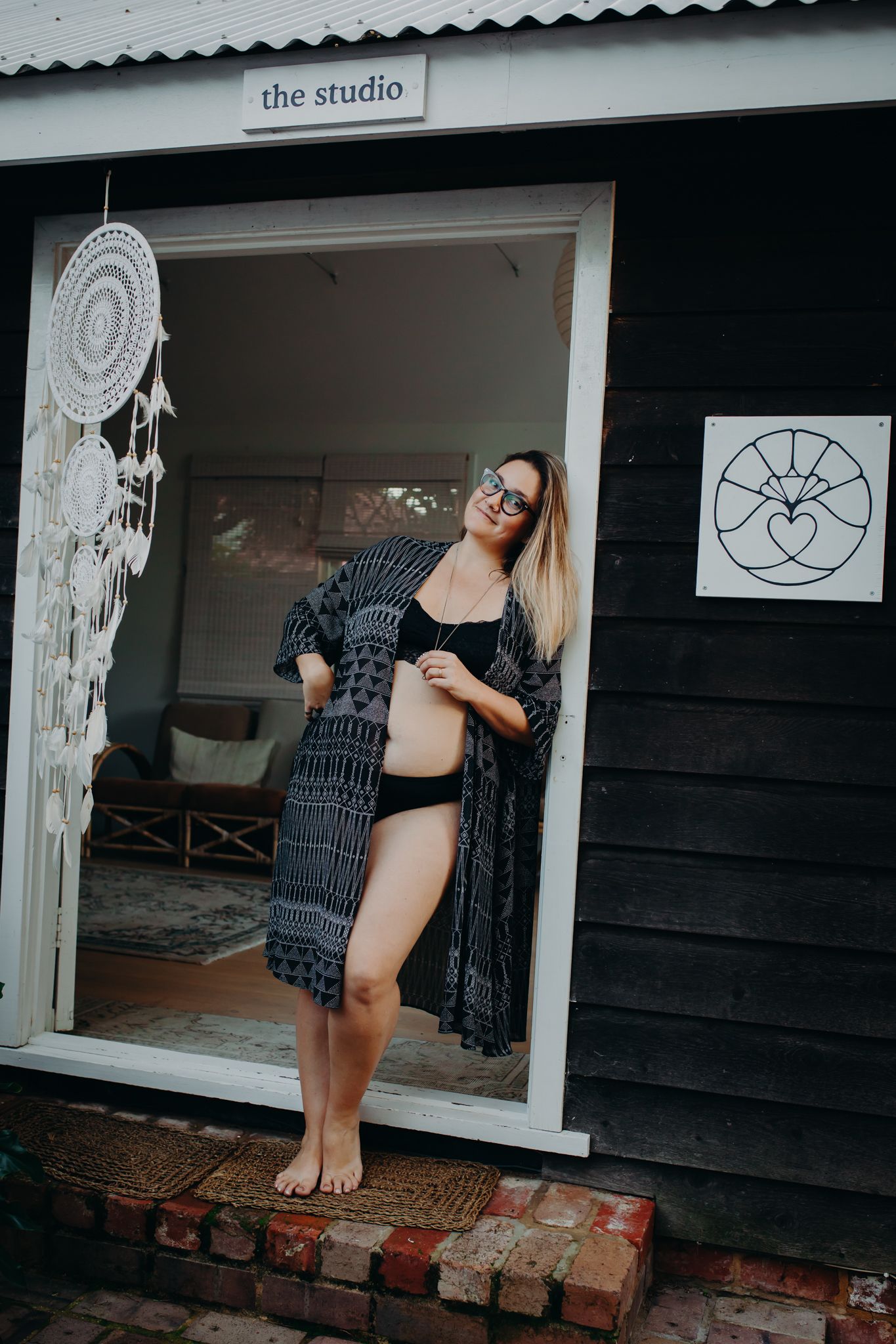 Person in patterned robe standing in doorway of studio building.