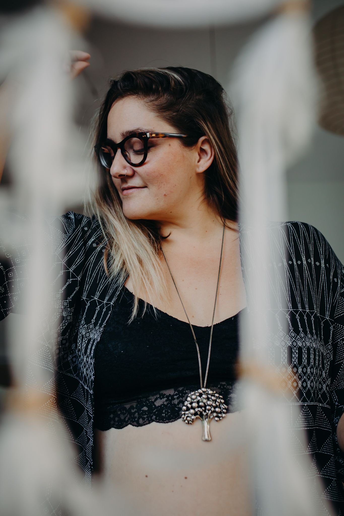Portrait through decorative elements showing person in black top and cardigan.