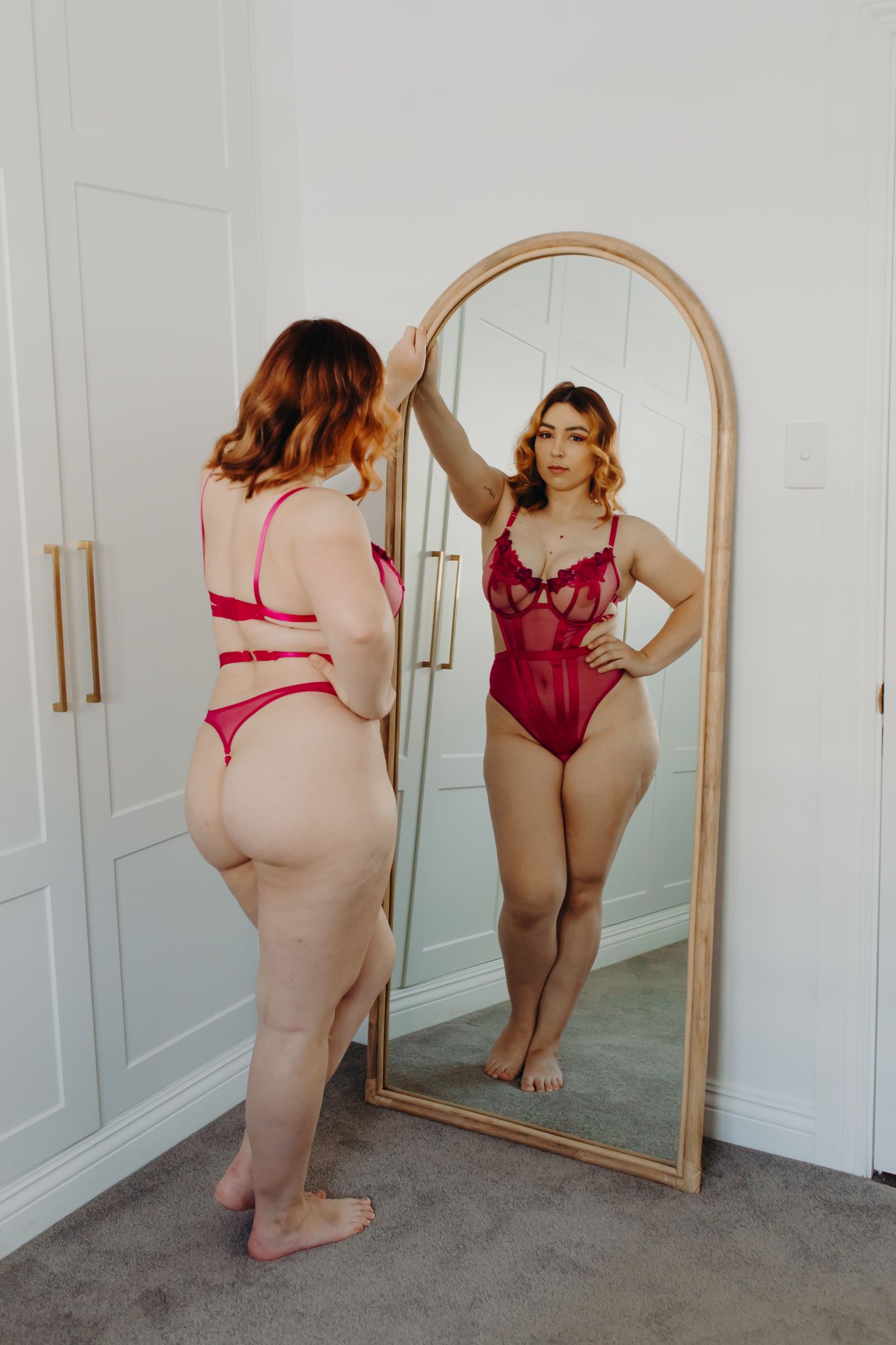 Full length mirror reflecting burgundy lingerie against white closet doors.