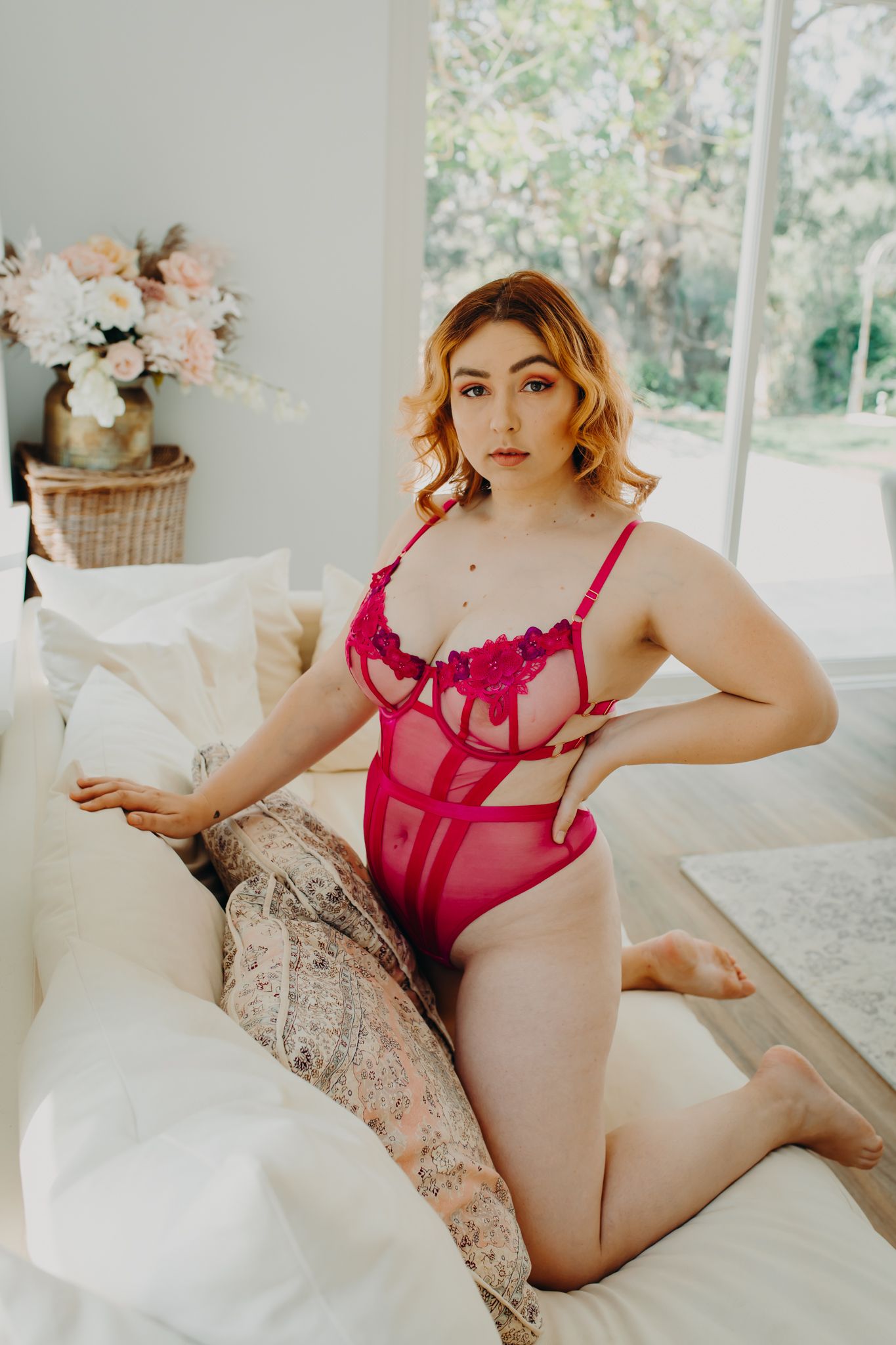 Boudoir photo session featuring red lingerie in a bright sunlit room with flower decor.