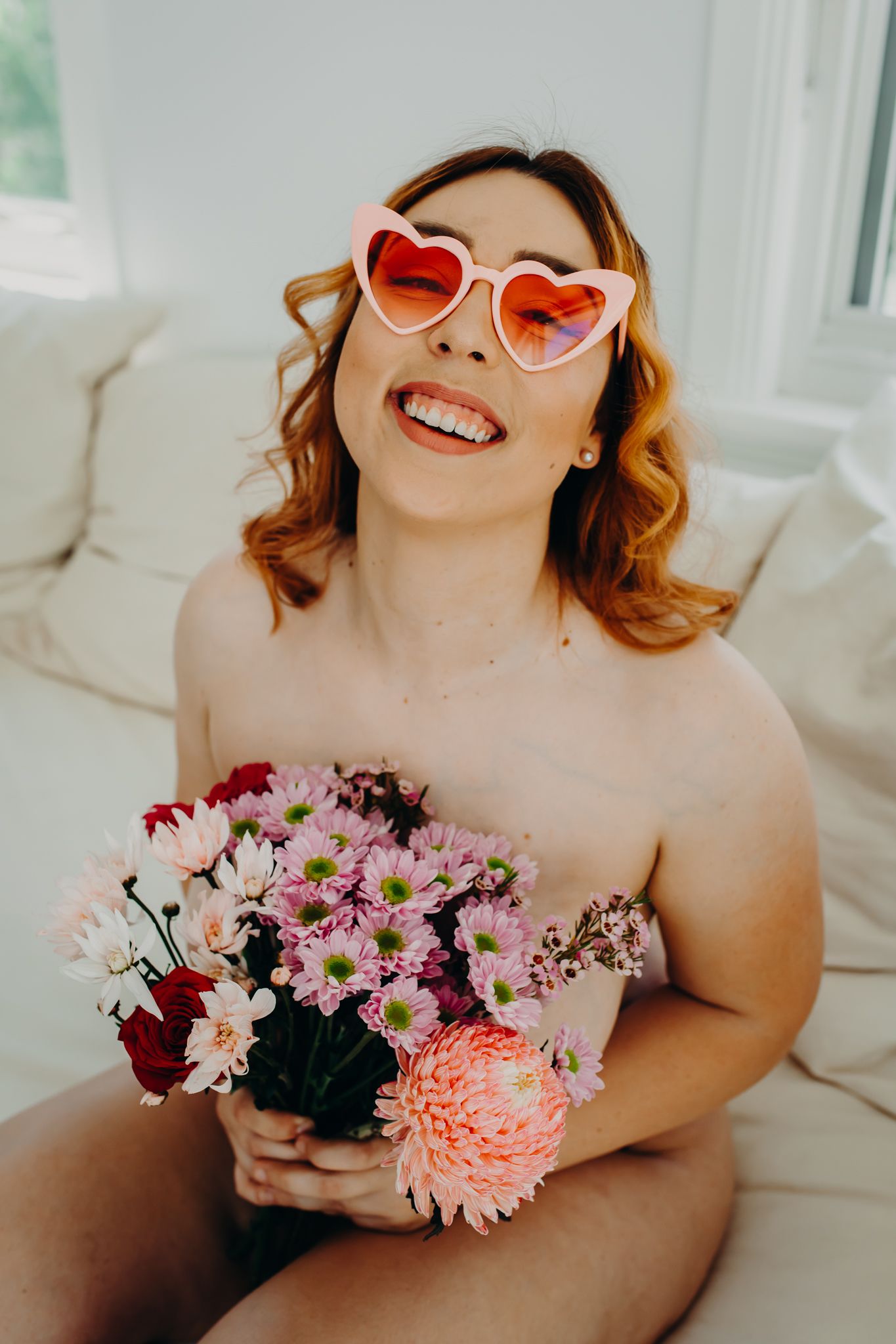 Fun portrait with heart sunglasses holding colorful bouquet of fresh flowers.
