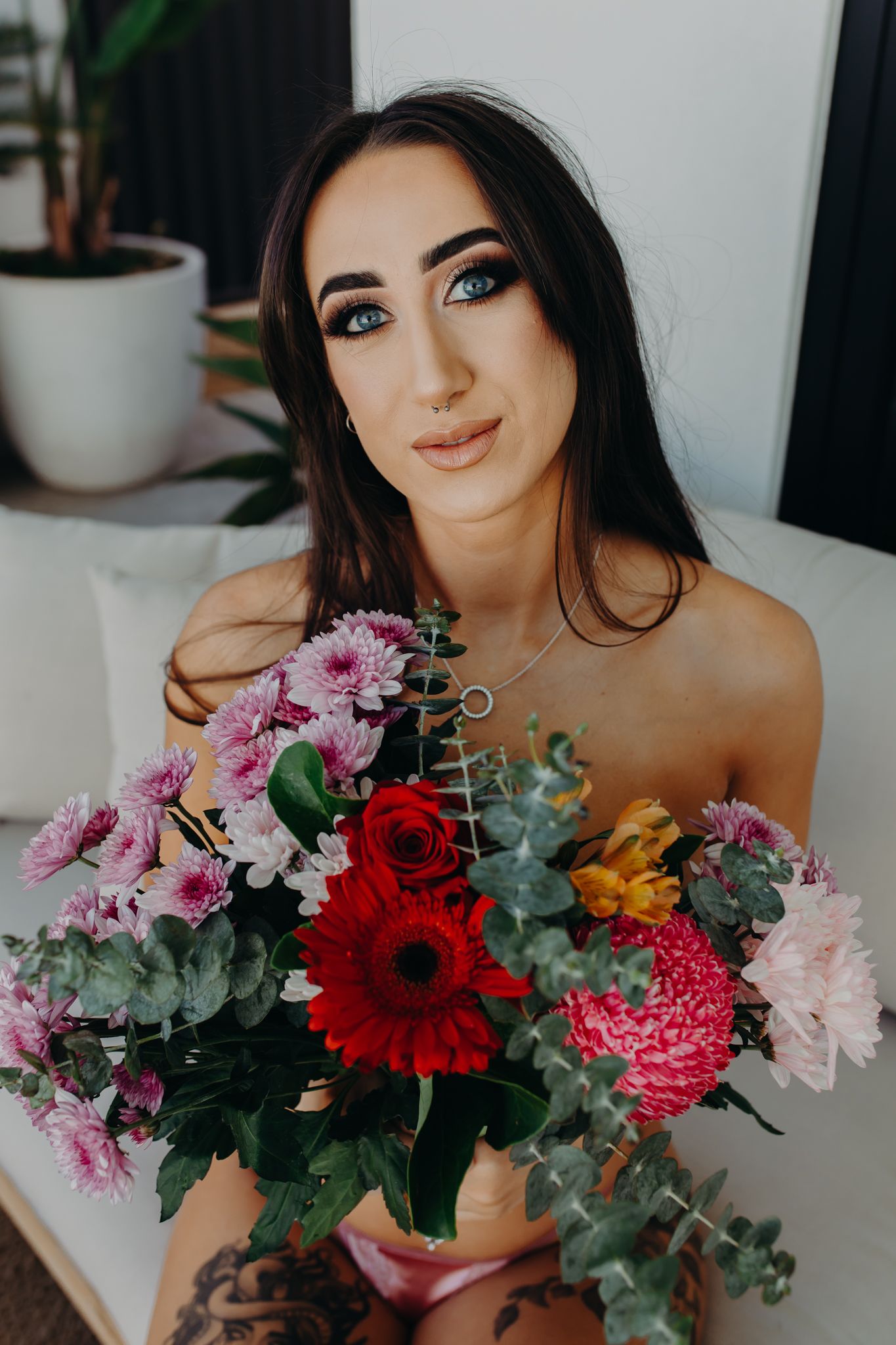 Colorful floral arrangement with gerbera daisies, roses and pink carnations against white background.