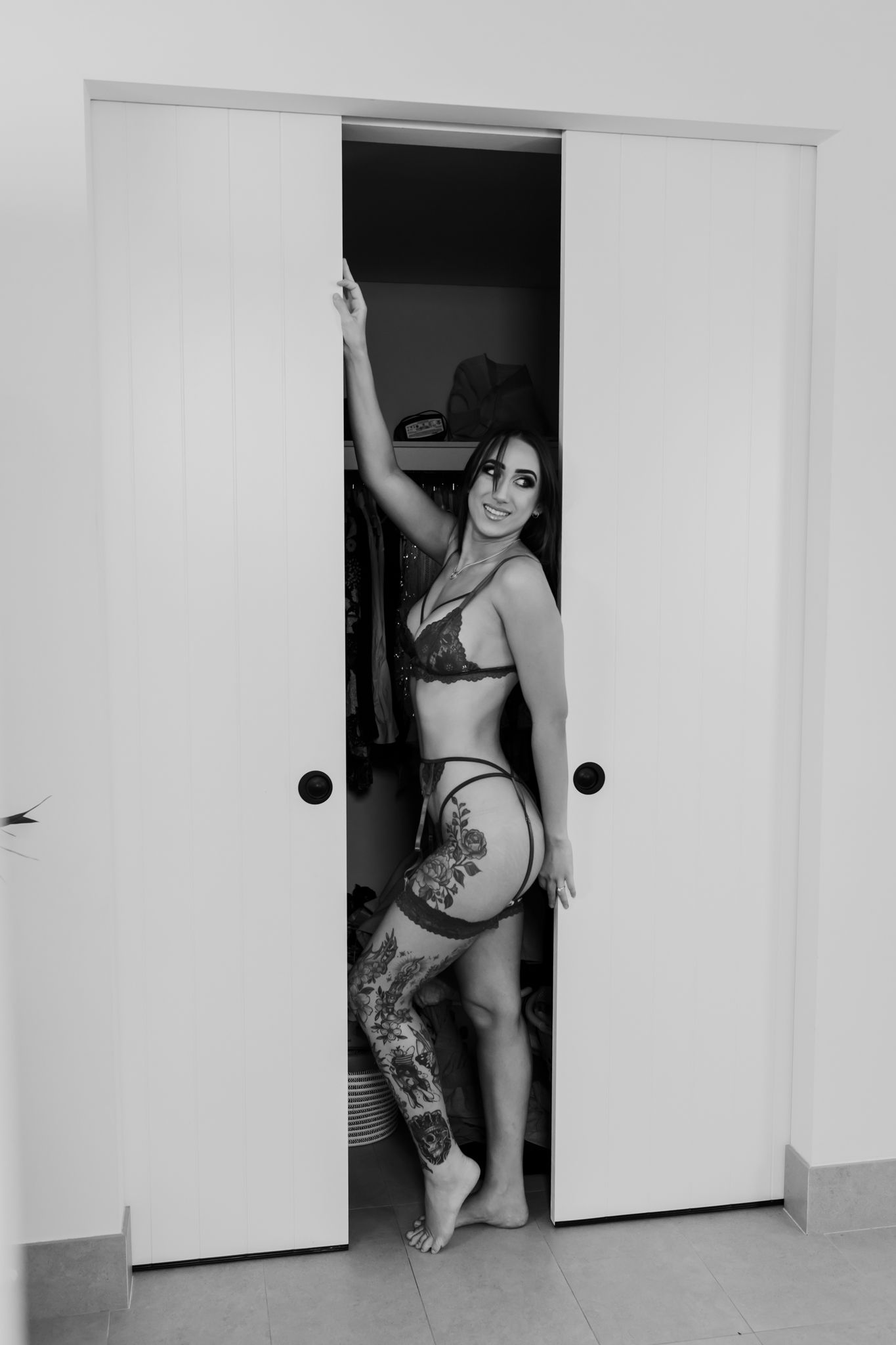 Black and white boudoir photo taken in a doorway with modern sliding doors.