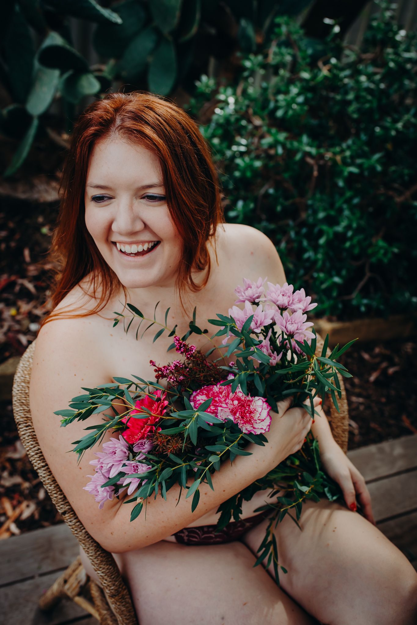 Natural portrait holding colorful flower bouquet with pink and red blooms outdoors.
