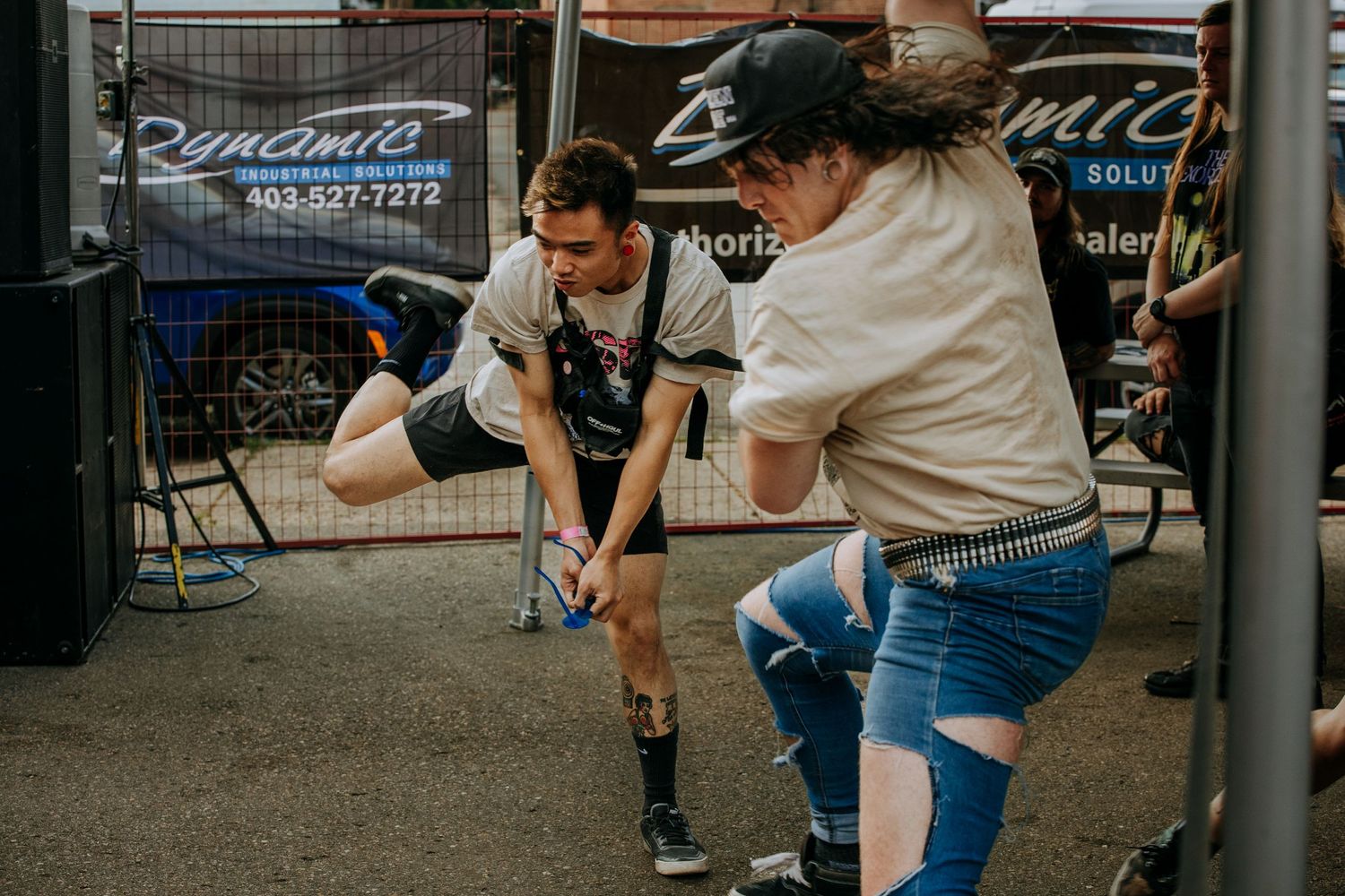 Two people engaged in an energetic dance move on a paved outdoor area.