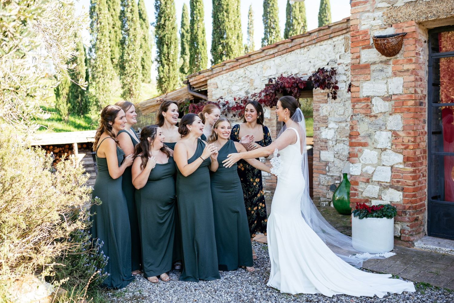 Bridesmaids in green dresses react to bride's dress reveal on her wedding day in Tuscany.