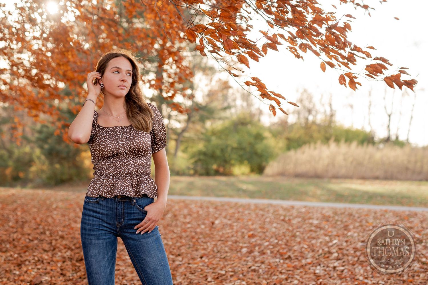 Fall outdoor portrait with orange leaves wearing animal print top and jeans.