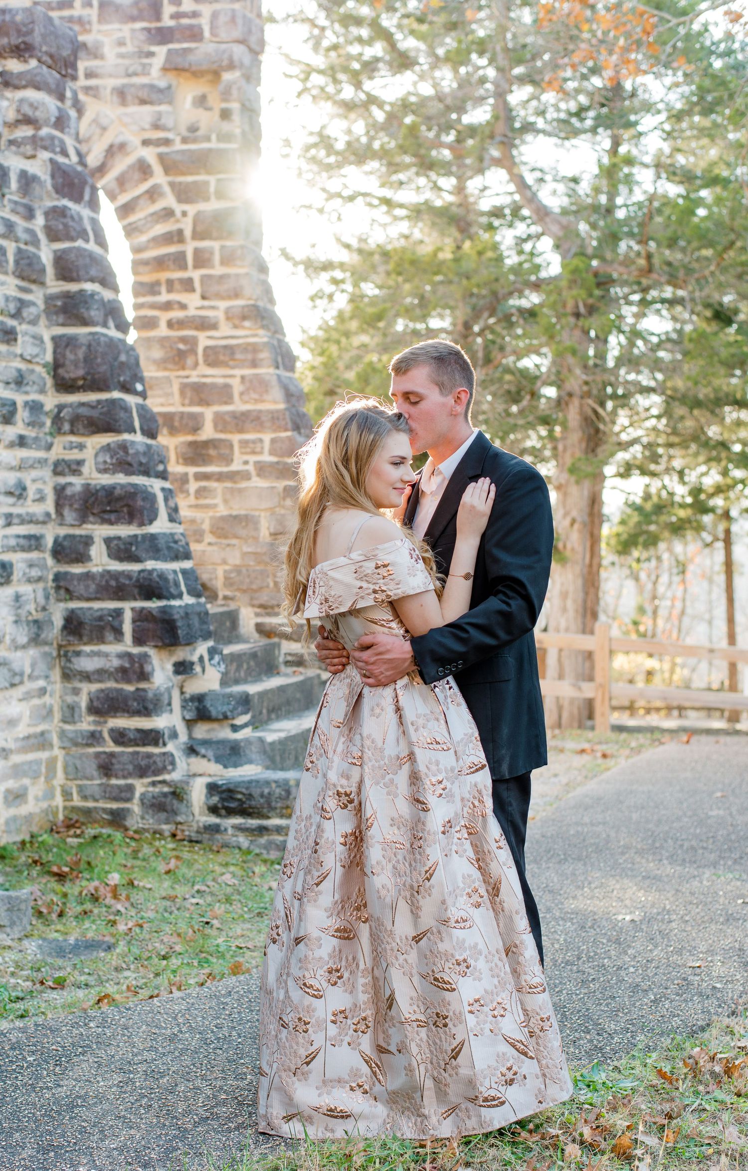 A romantic moment captured at a stone church with a couple embracing, the person wearing a blush floral ball gown.