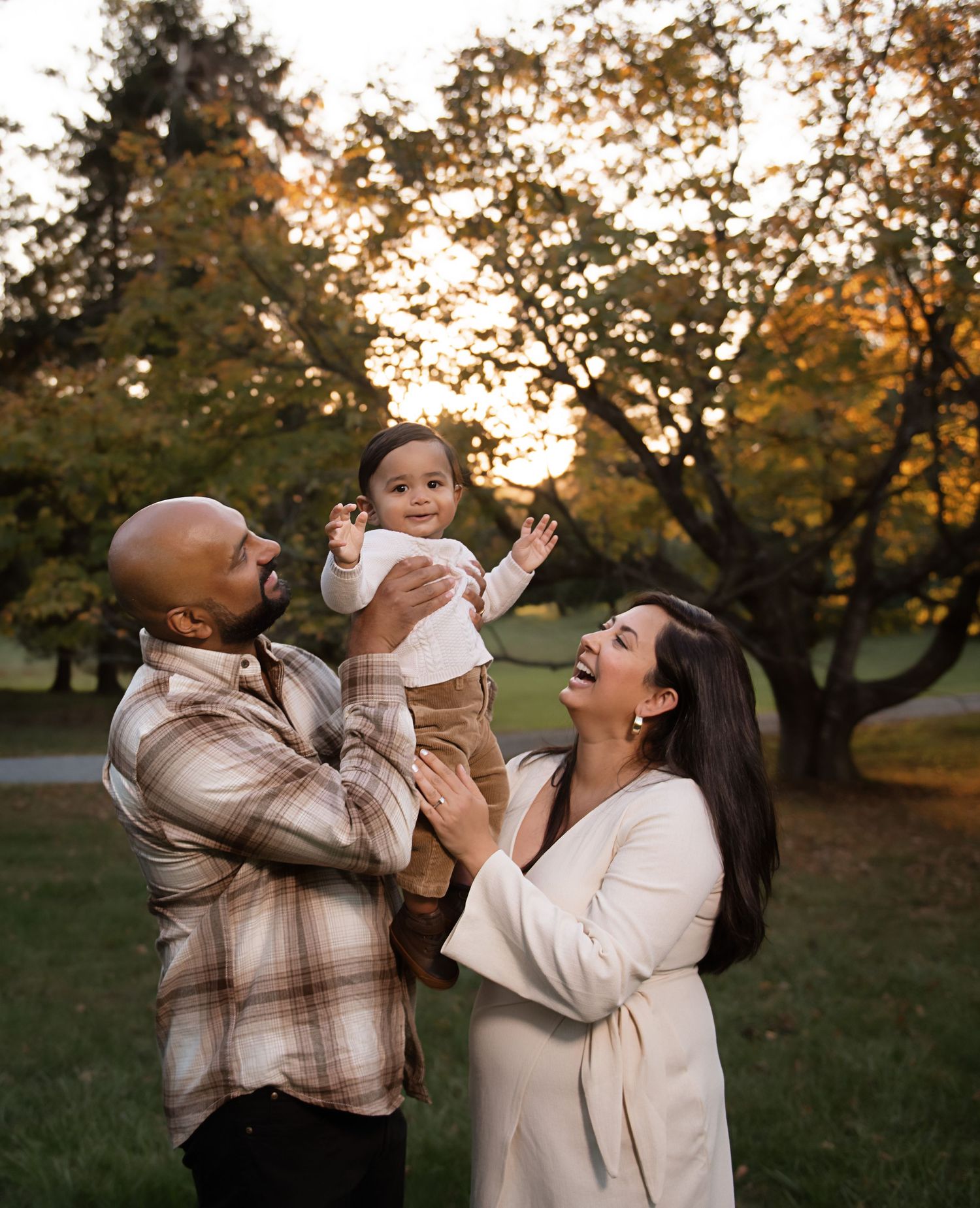 A joyful family moment captured outdoors during golden hour in an autumn park setting.