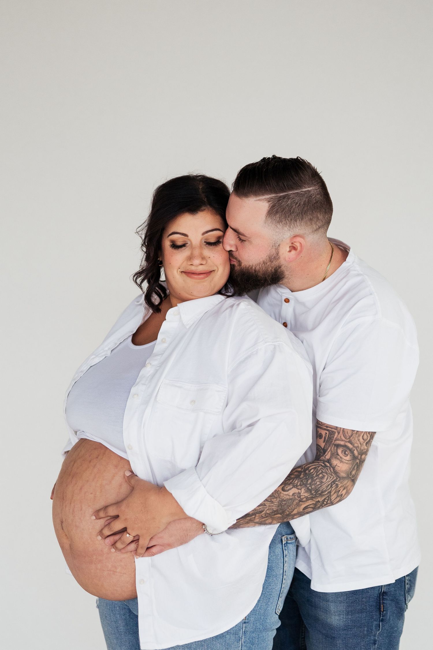 Maternity photoshoot with couple in white shirts showing pregnancy progression.