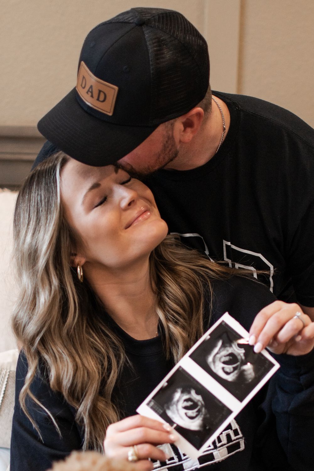 Couple holding ultrasound photos while sharing emotional moment together.