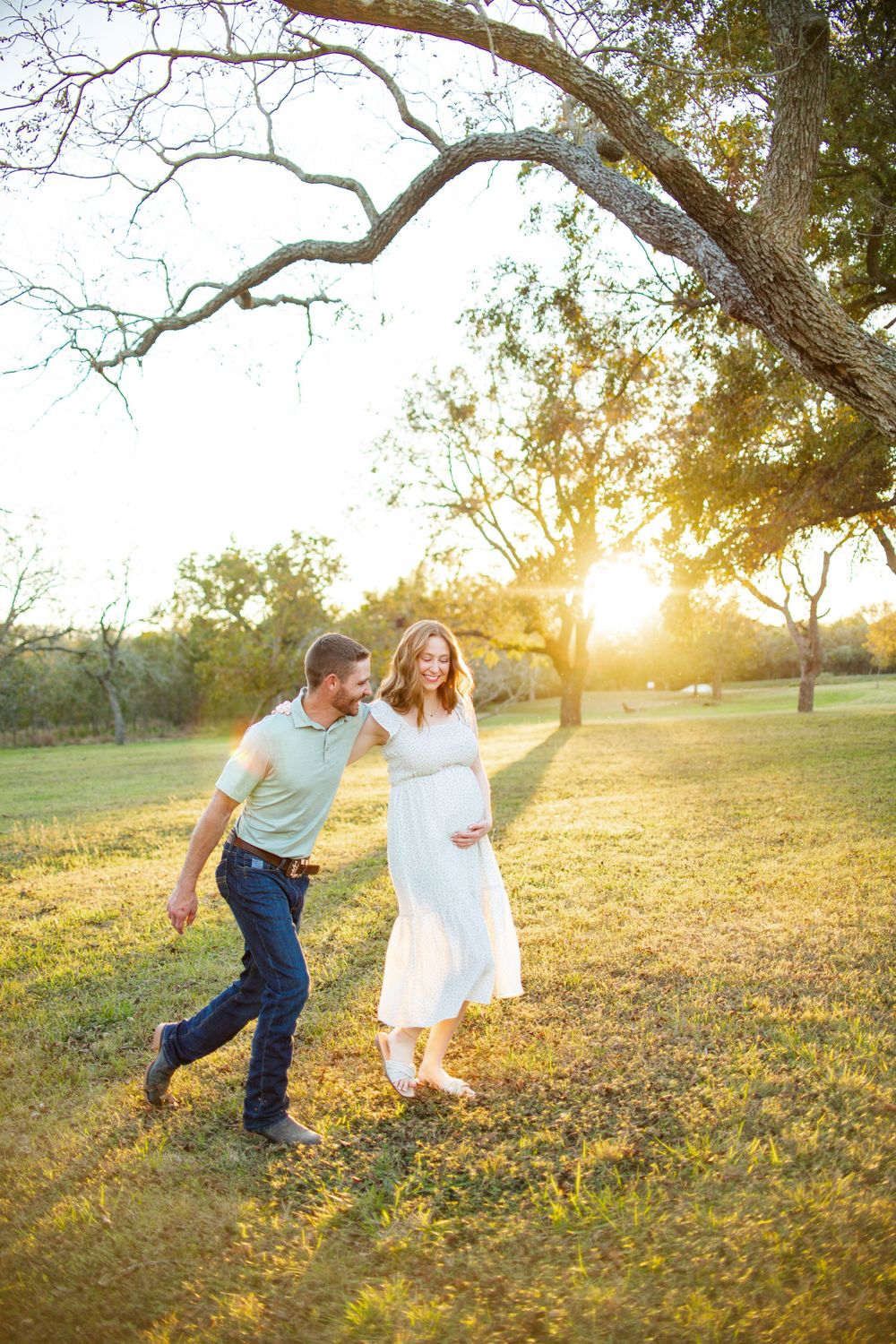 Playful couple walking through a sun-drenched park during golden hour.
