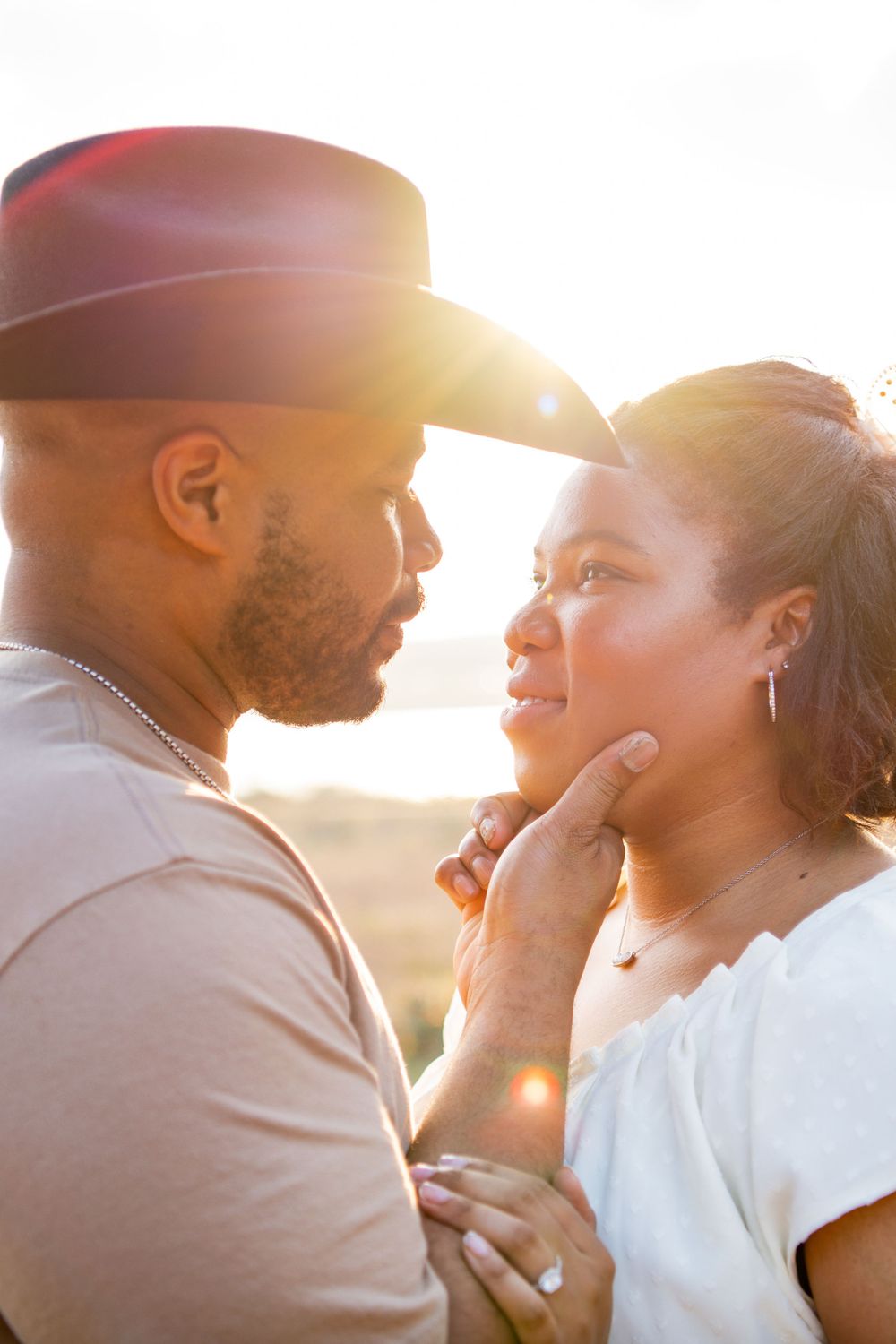 An intimate couple shares a loving moment at sunset with beautiful lens flare.