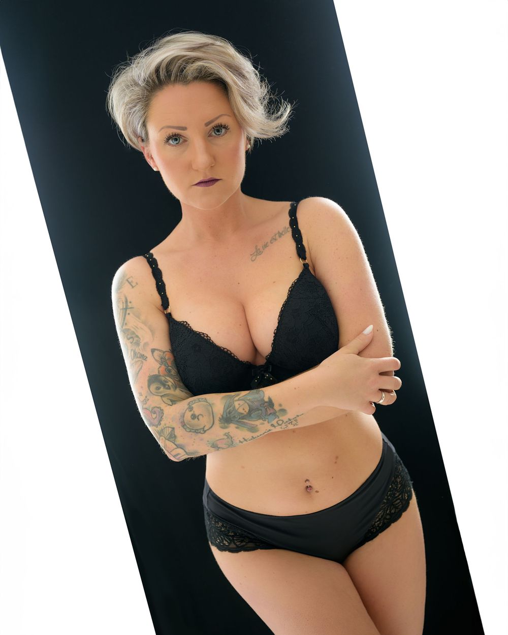 Model in black lingerie poses against white backdrop in artistic boudoir photo series.