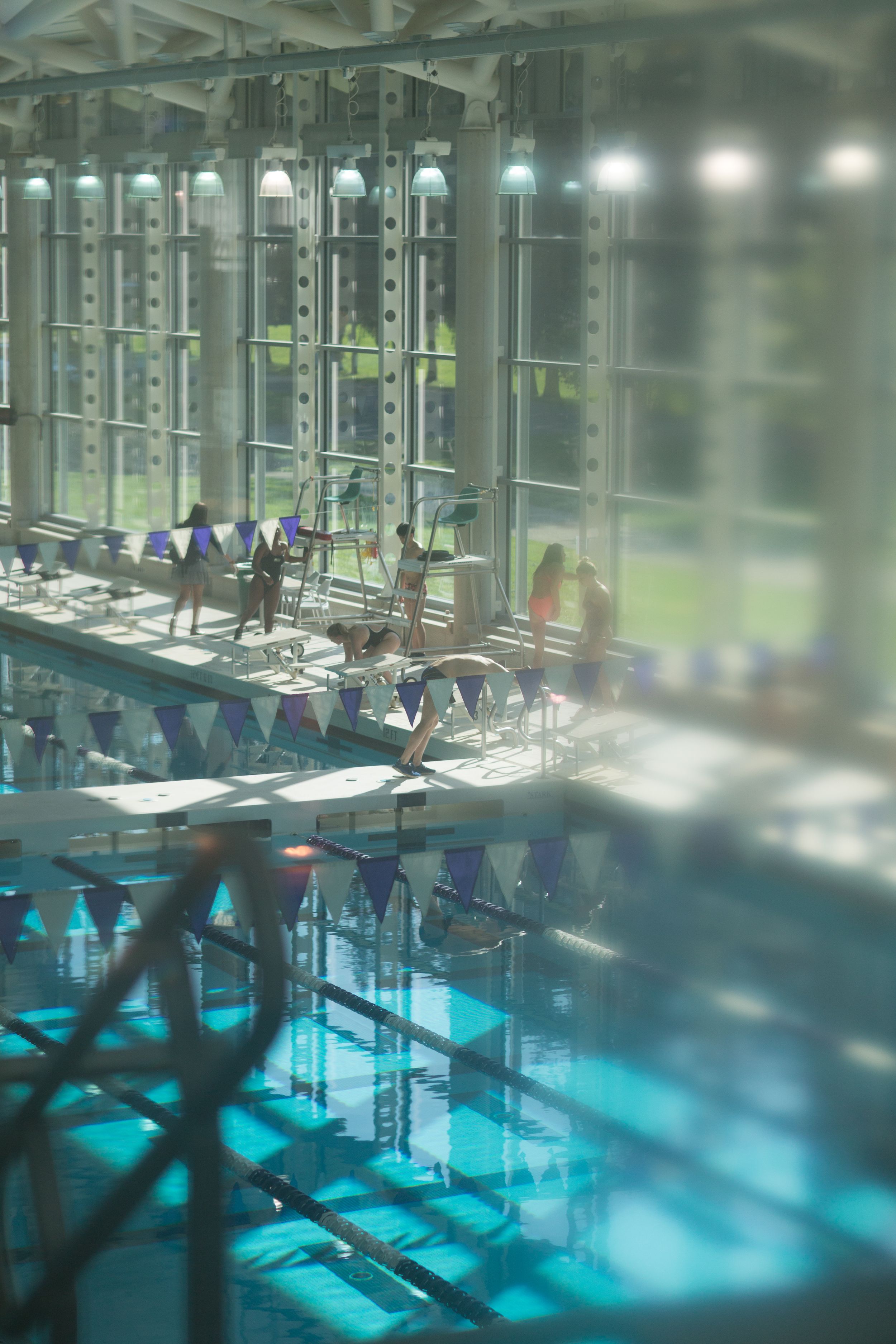 An illuminated indoor swimming pool with blue water and architectural columns at night.
