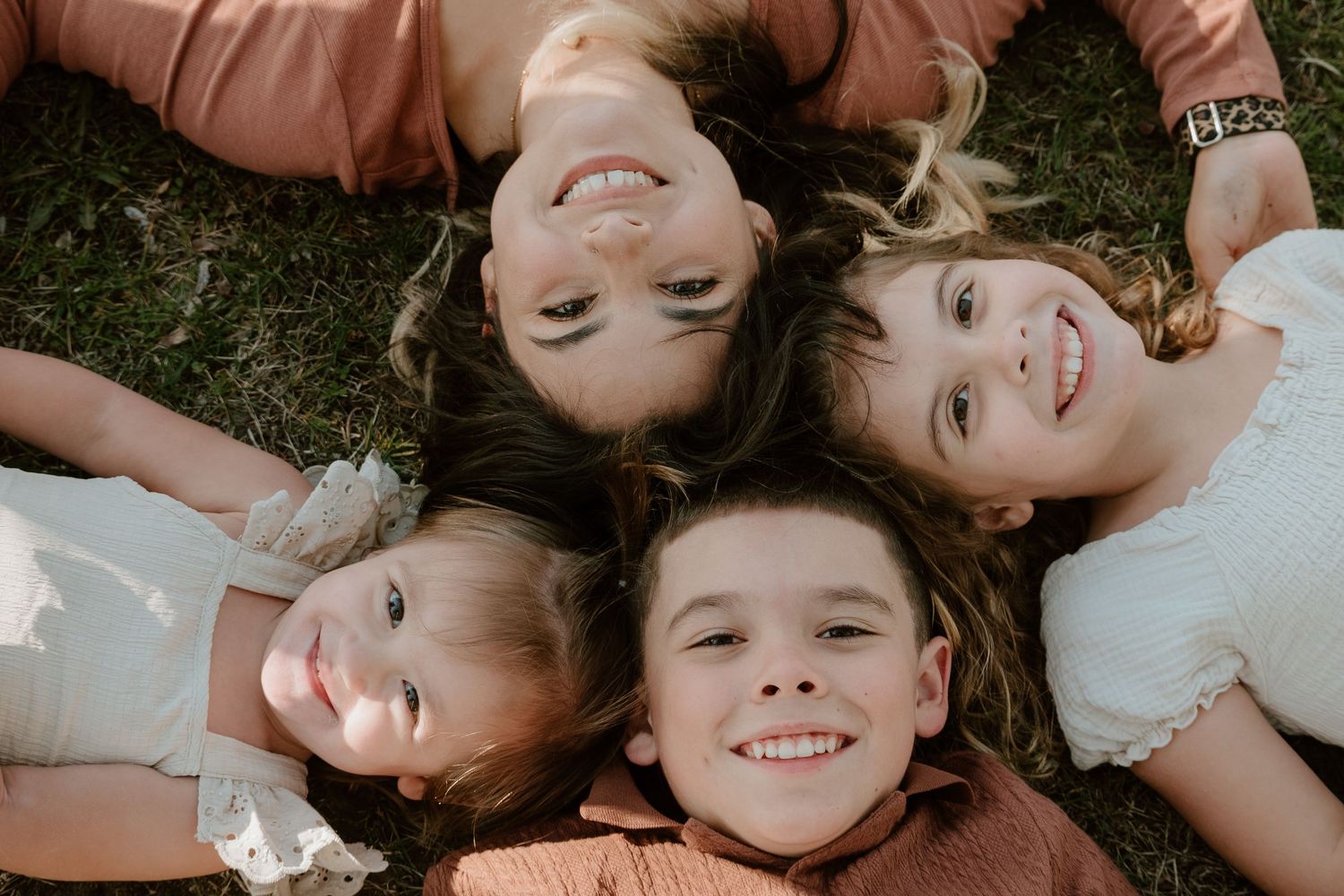 A young family of five poses on a wooden boardwalk, with children hugging on the ground.