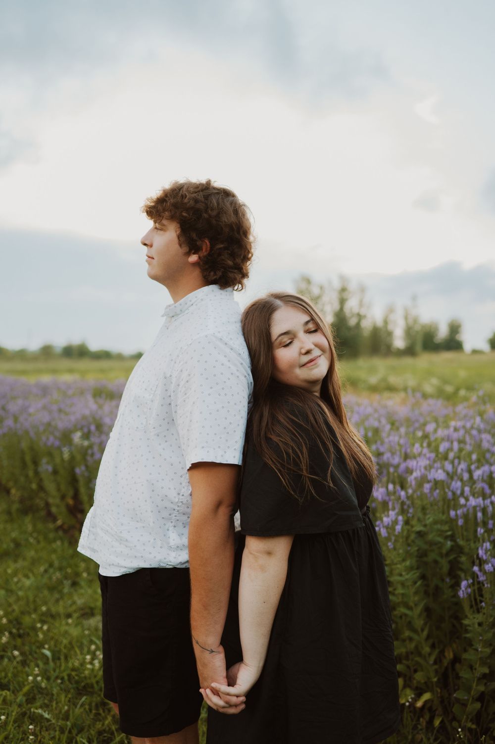 A couple stands together in a blooming purple wildflower field during golden hour, shown in multiple romantic poses.