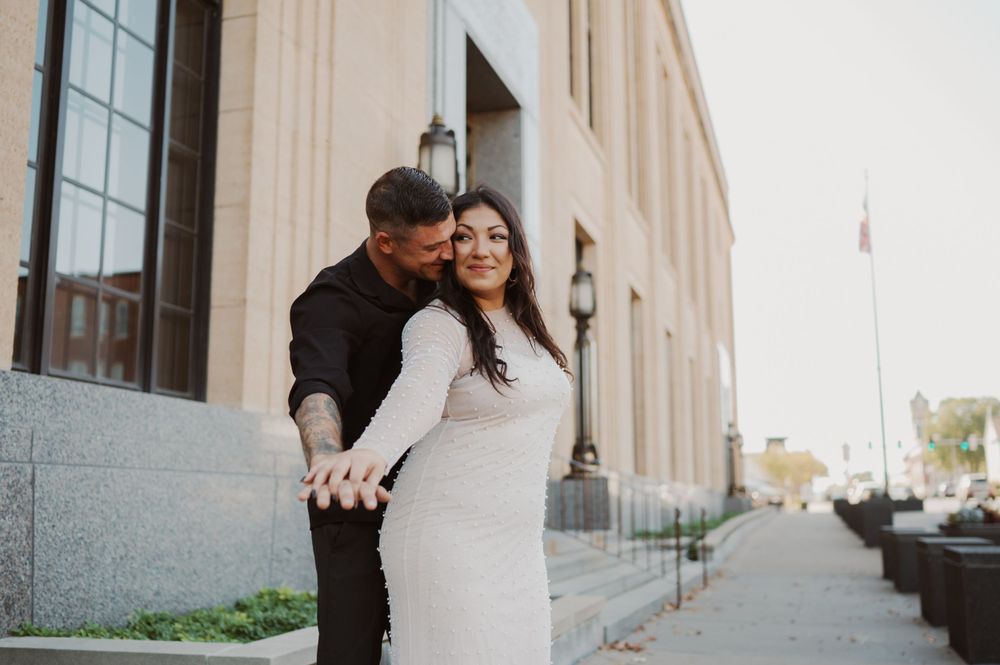 A couple shares an intimate moment in an elegant archway setting.