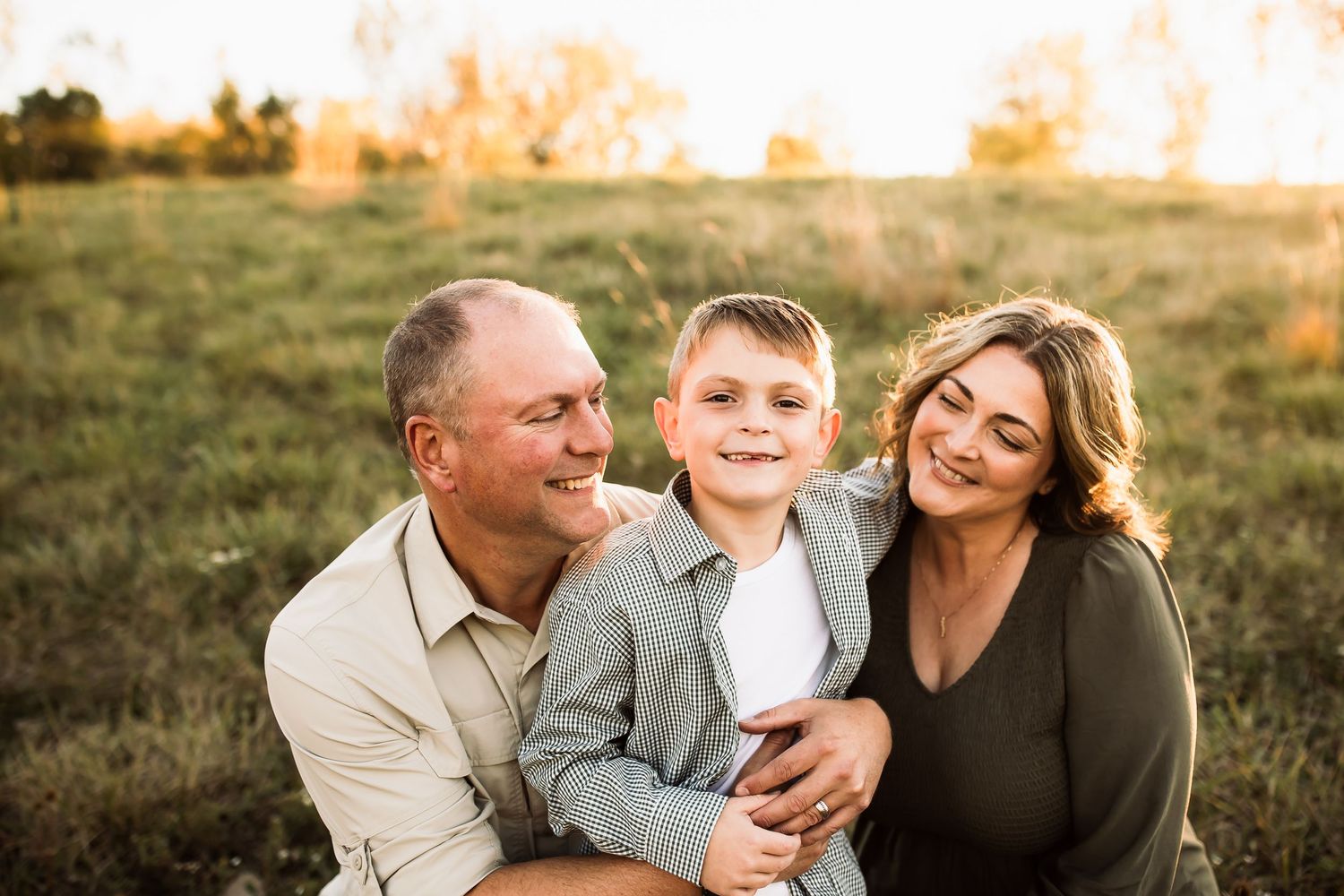 A family sits together in a grassy field during golden hour sunset.