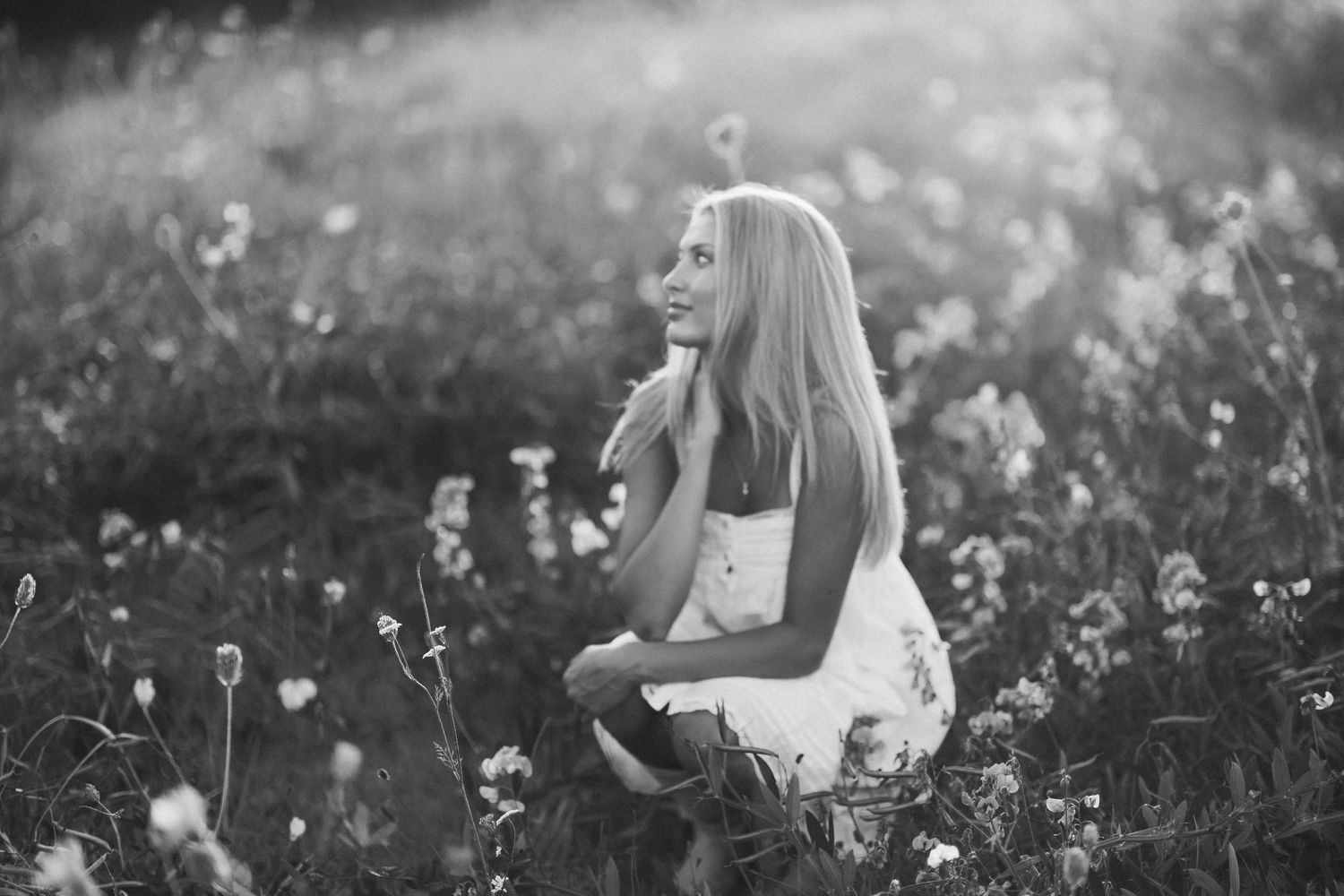 Figure sitting in tall grass during golden hour photography session.