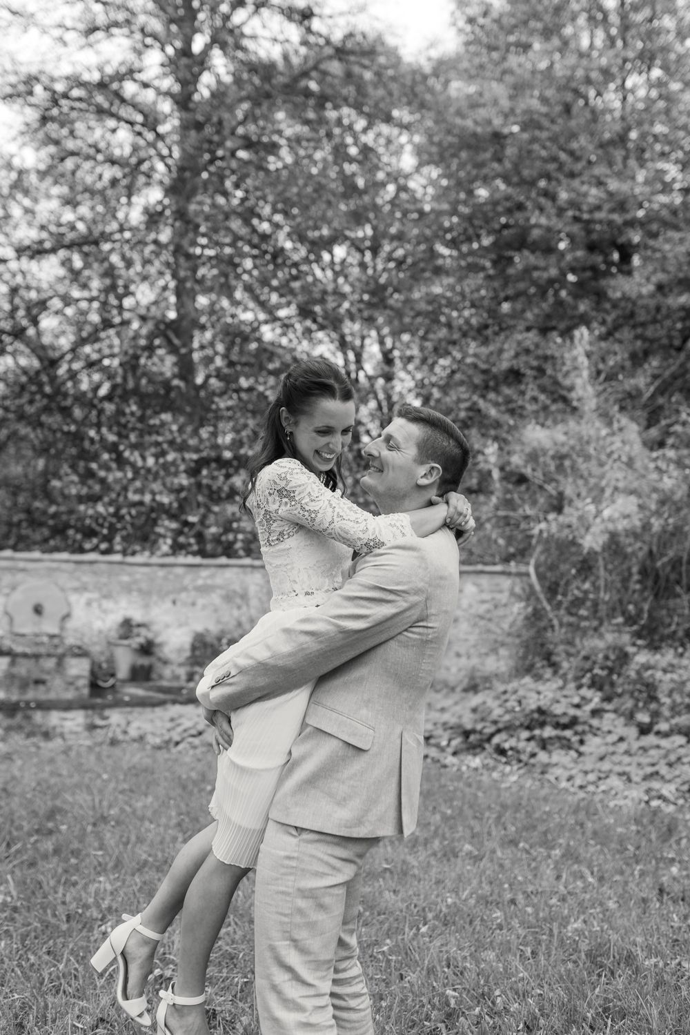 Ein romantisches Schwarz-Weiß-Foto eines liebevollen Paares, das sich in einer Gartenumgebung umarmt.
