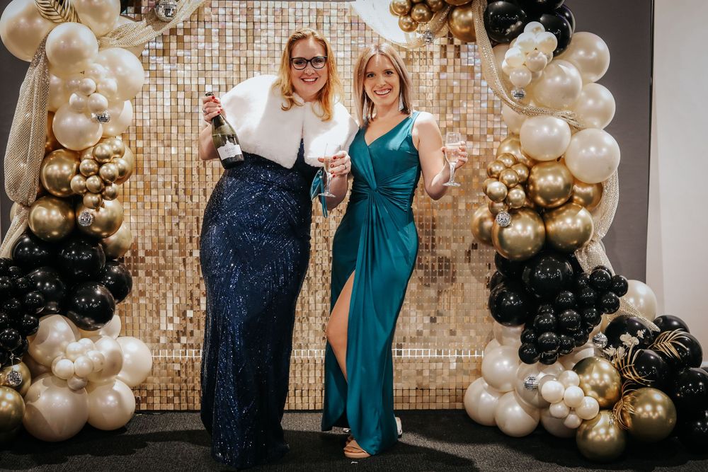 Stunning event venue decorated with metallic balloons and sequined wall backdrop.