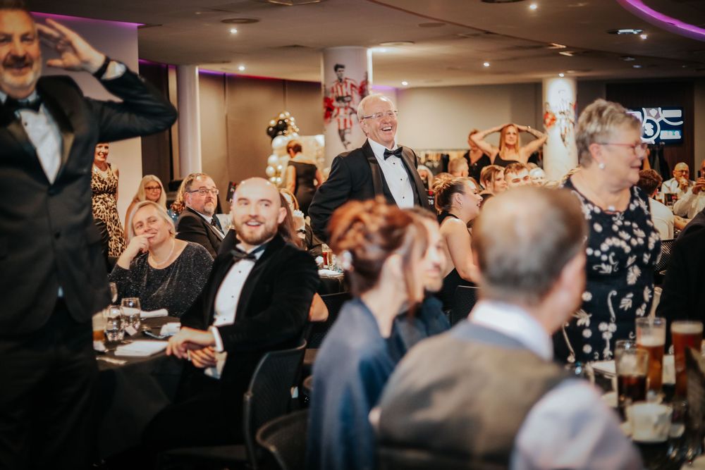 Formal dinner event with guests enjoying entertainment in dimly lit venue.