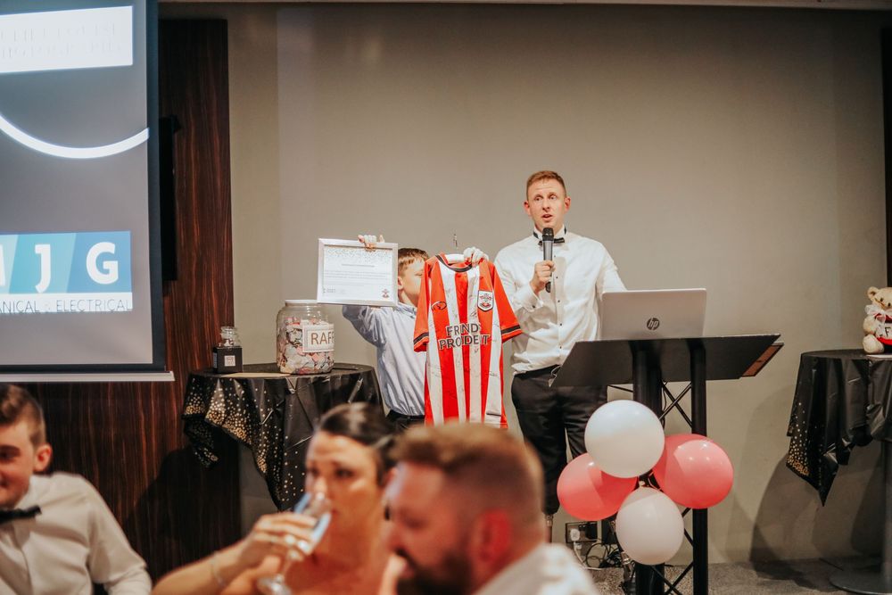 Event presentation with sports jerseys displayed on projection screen.