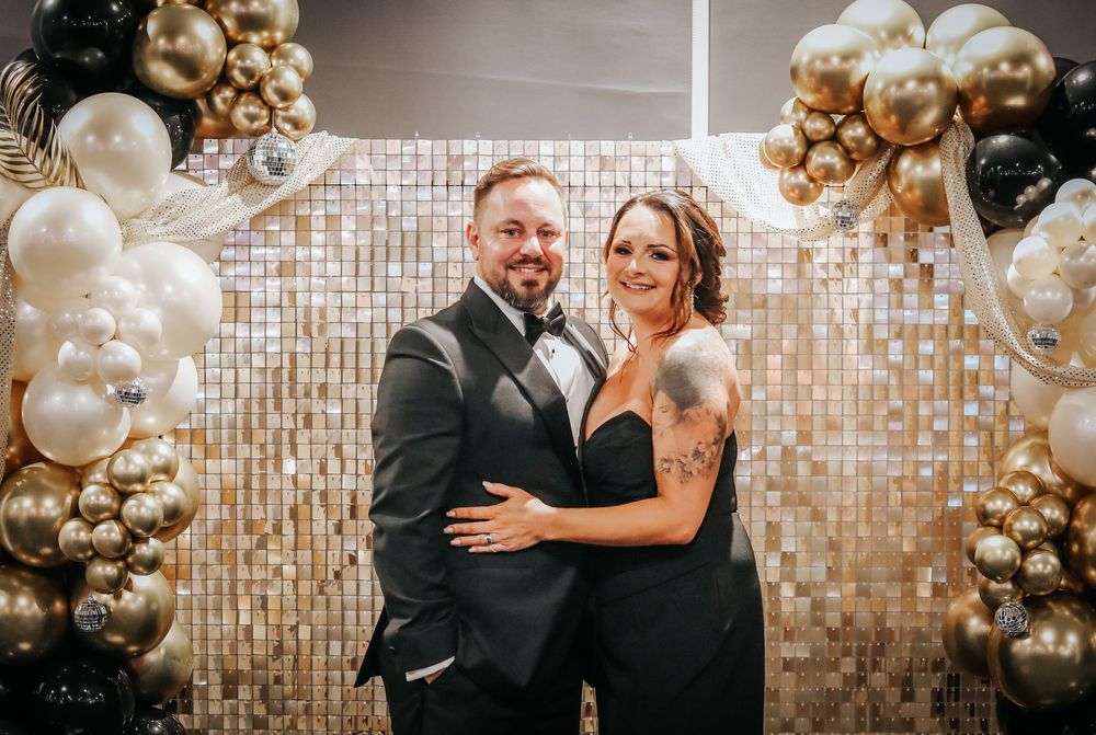 Elegant celebration setting with gold and black balloon decorations against a sparkly backdrop.